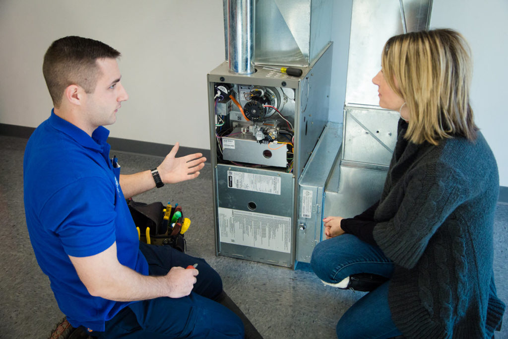 An Arctic HVAC tech showing the customer what is wrong with the furnace
