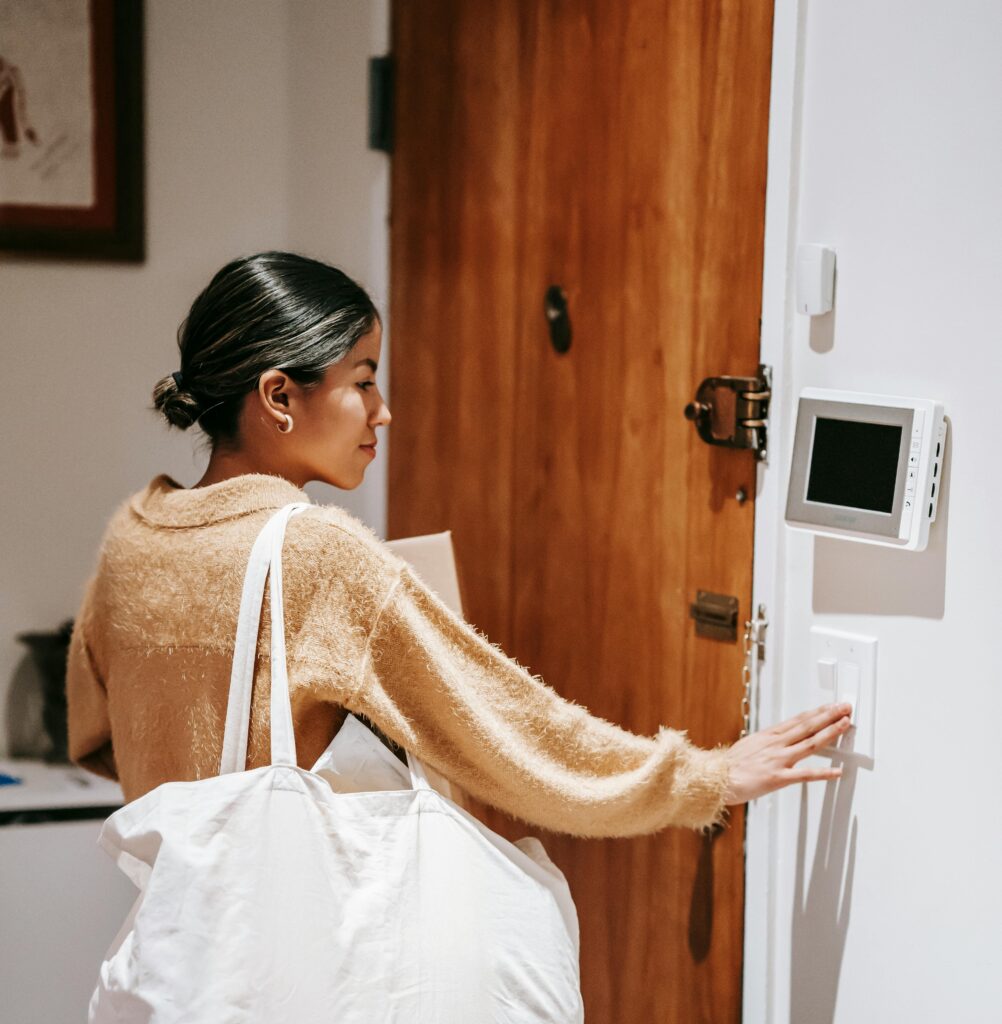 lady adjusting thermostat near door