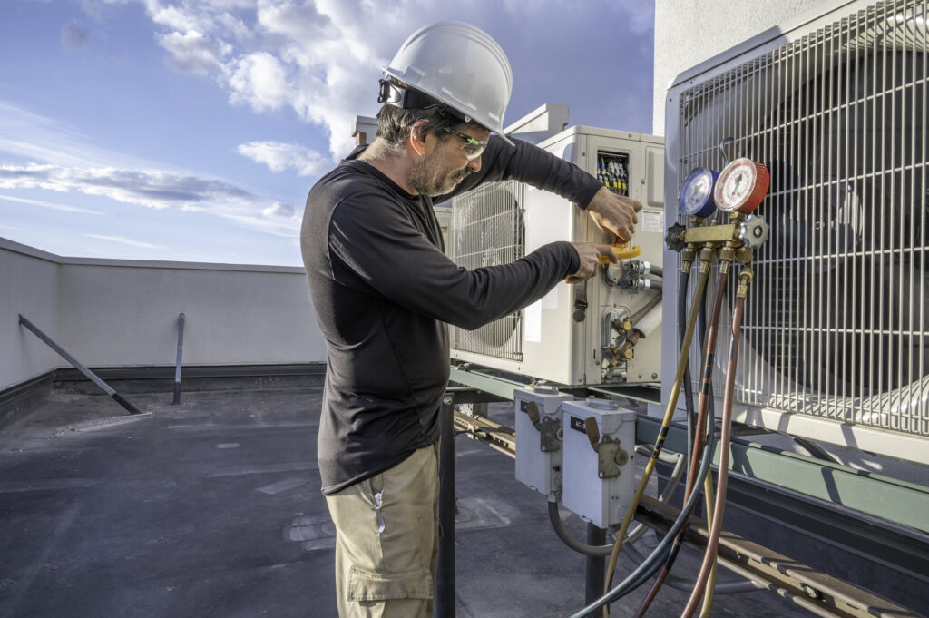 HVAC tech checking a rooftop air conditioner amps with a meter