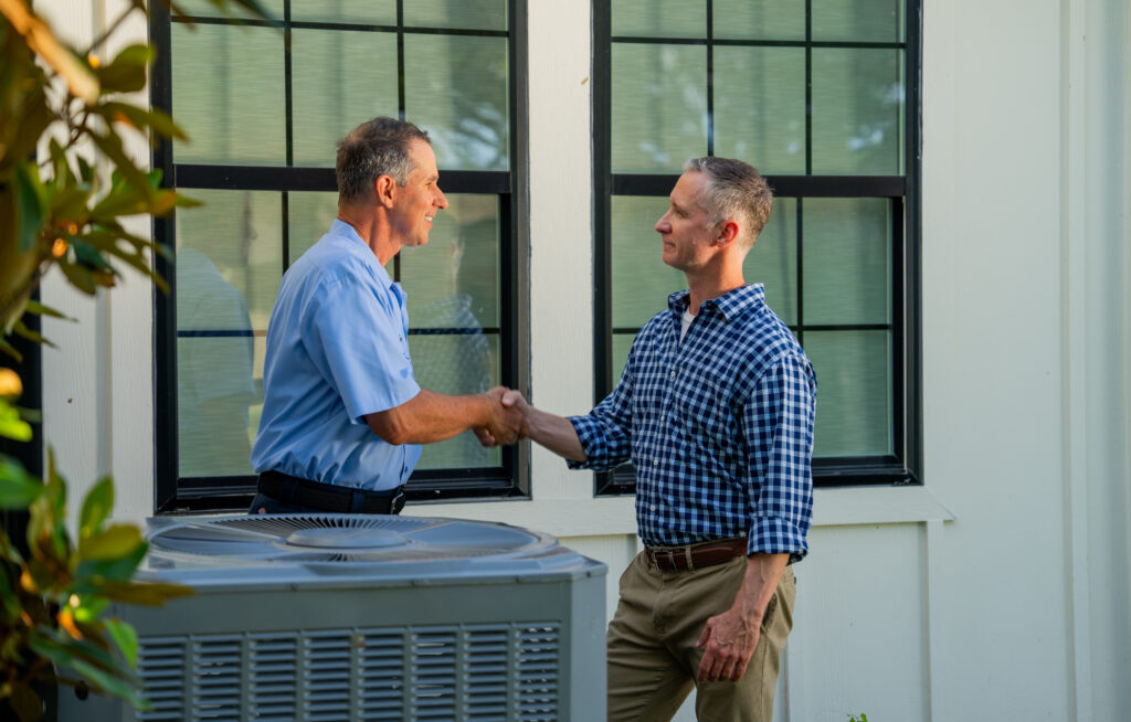 AC tech shaking hands with customer over air conditioner